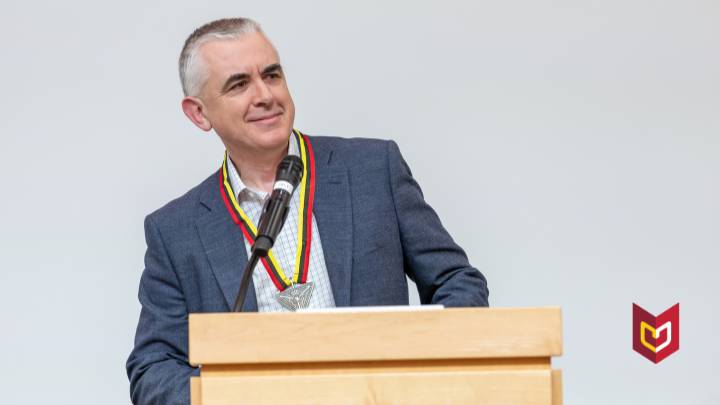 David I. Smith standing behind a podium wearing the Presidential Award medallion.